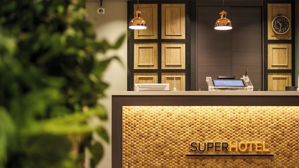 Un mostrador de recepción con diseño de panal de madera y el texto 'SUPER HOTEL'.