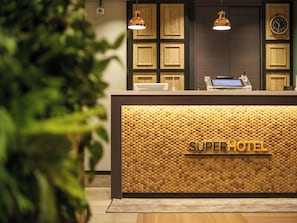 Vastaanottotiski, jossa on puinen, hunajakennokuvioitu pinta ja jossa lukee teksti: ”SUPER HOTEL”.