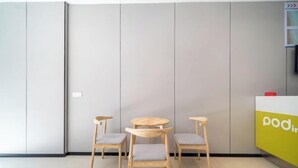 Un interno moderno con una reception, tre sedie di legno e un pavimento piastrellato.