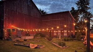 A rustic barn with string lights, wooden benches, and raised garden beds. - 5-bedroom FarmHouse with WiFi,  Large Gathering Room, Dining kitchen in Nappanee (Nappanee)