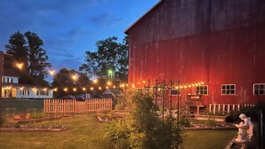 A red barn with a wooden fence and string lights in a backyard. - 5-bedroom FarmHouse with WiFi,  Large Gathering Room, Dining kitchen in Nappanee (Nappanee)