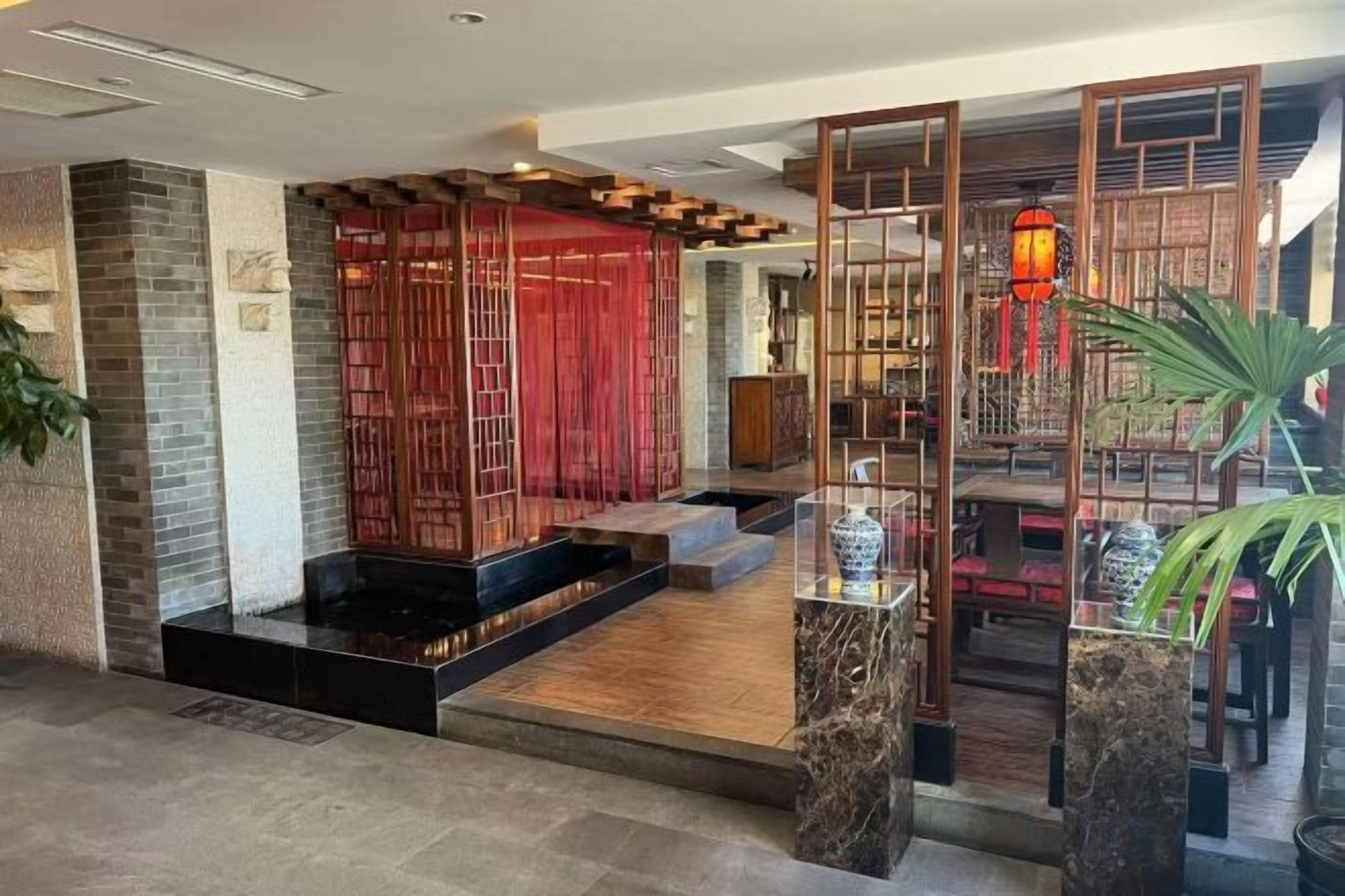 Un interior de estilo tradicional con piso de madera, un separador rojo y una zona de estar con mesa y sillas.