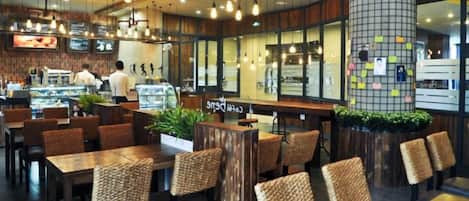 Restaurante com móveis de madeira, luminárias pendentes e um grande pilar coberto de anotações.