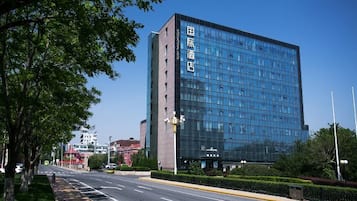 A modern hotel building with a glass facade and a clear blue sky in the background.