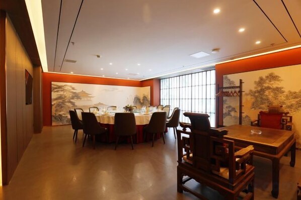Un coin repas avec une table ronde, des chaises et un tableau de style asiatique traditionnel accroché au mur.