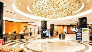A spacious lobby with a central circular marble floor, a large geometric ceiling light, and a reception desk with a modern design. - Yingkou International Hotel (Yingkou)