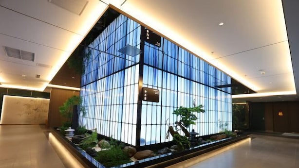 A modern reception area with a glass partition, a reception desk, and a small indoor garden. - Yingkou International Hotel (Yingkou)