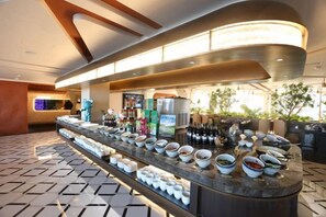 A buffet bar with a variety of food items and beverages, a seating area with a patterned floor, and a modern interior design. - Yingkou International Hotel (Yingkou)