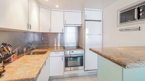 A modern kitchen with white cabinets, stainless steel appliances, and a granite countertop.
