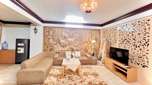 Un salon comprenant un ensemble de canapés de couleur beige, une table basse, un meuble pour la télévision et un panneau décoratif mural.