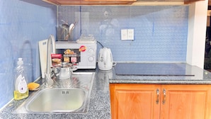 Une cuisine compacte avec des meubles en bois, un évier en acier inoxydable, un grille-pain et une bouilloire.