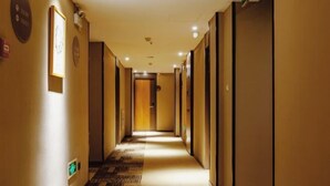 A hotel hallway with a carpeted floor, doors on both sides, and a sign on the left wall. - Homeinn Hotel (Weifang Xinhua Road Shengli East Street City Government Plaza) (Weifang)