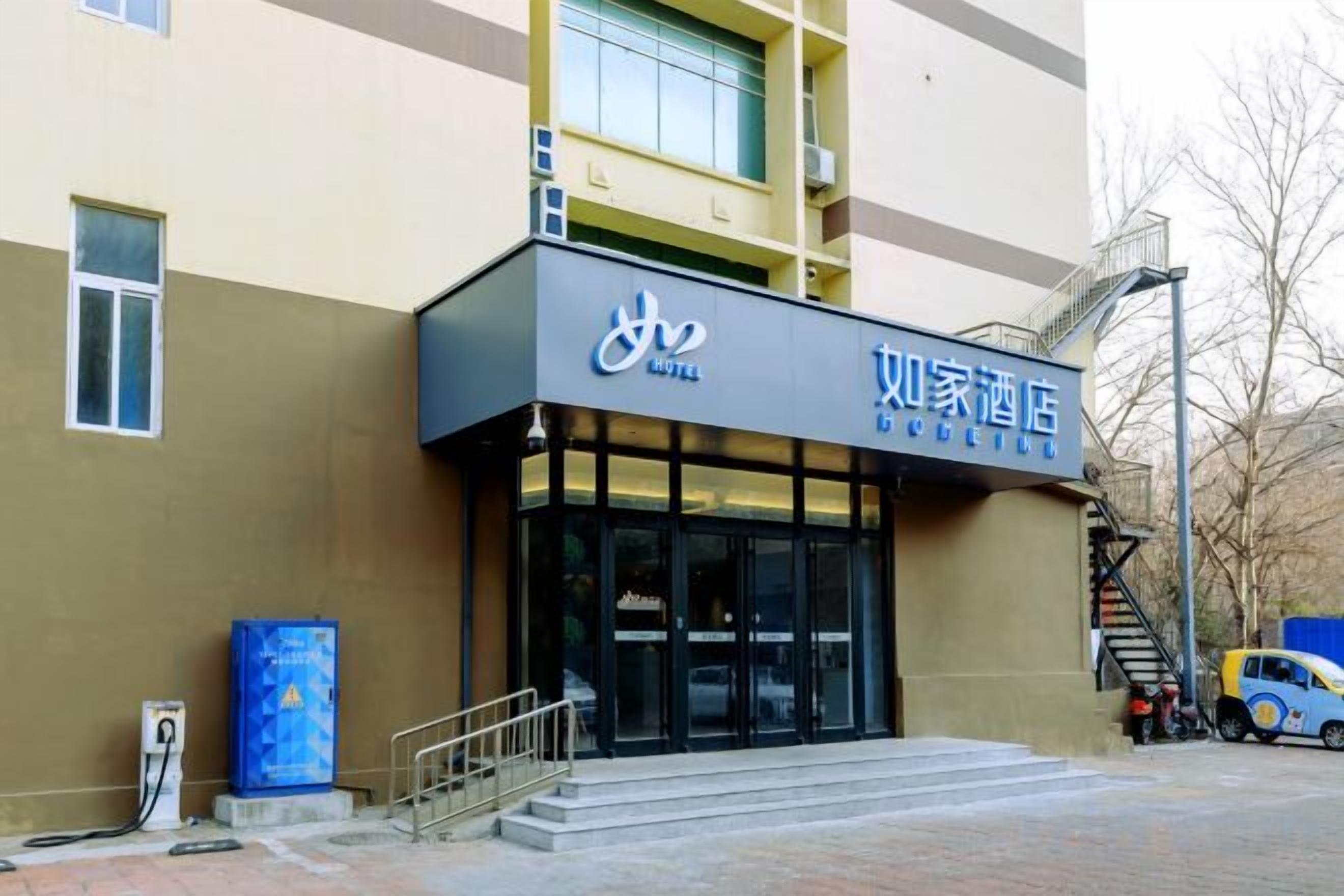 A hotel entrance with a sign, a staircase, and a parked car.