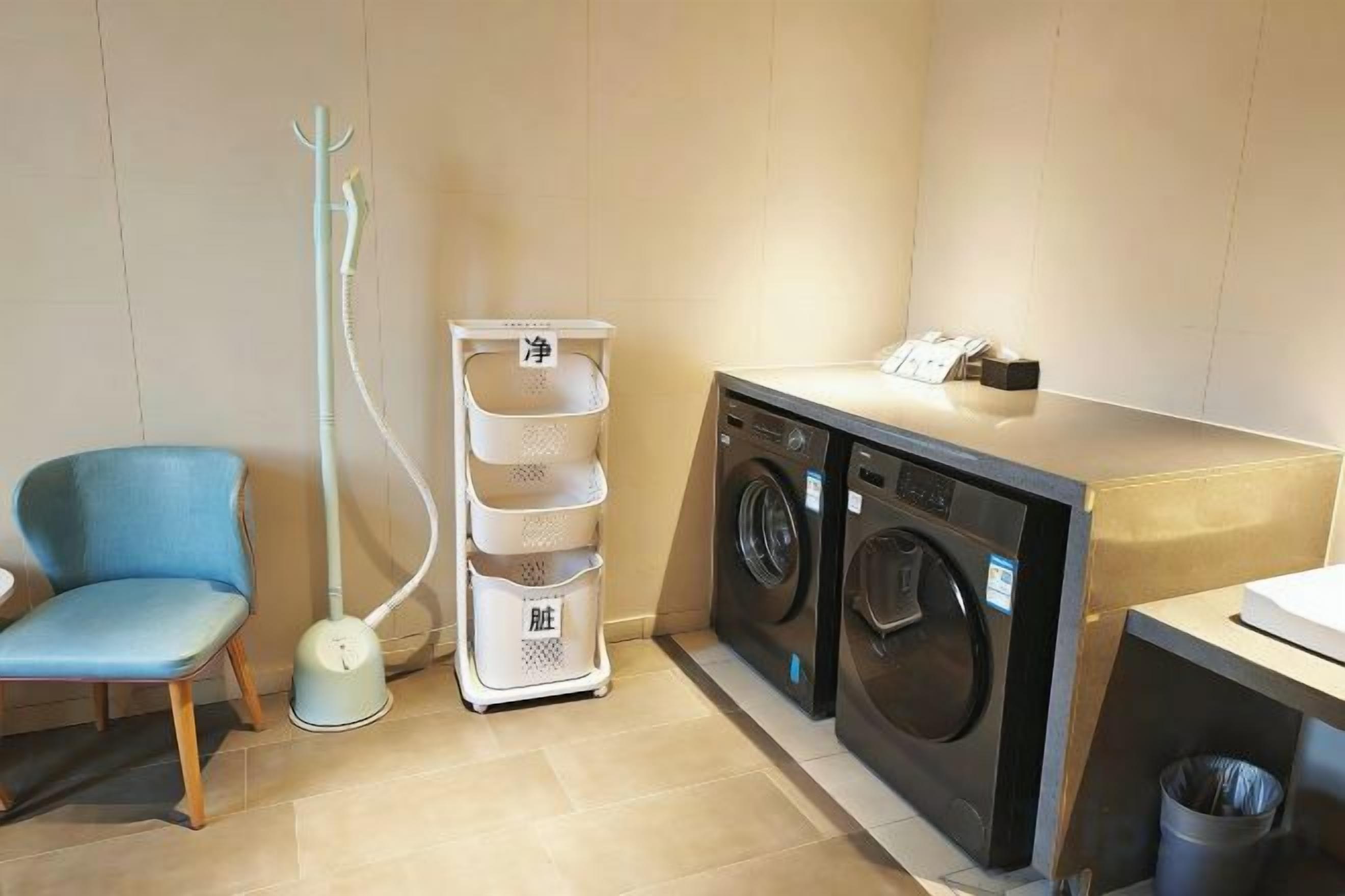 A laundry area with a washing machine, a drying rack, and a chair.