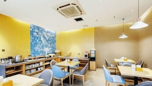 A restaurant with a yellow and blue tiled wall, wooden tables and chairs, and a television screen. - Homeinn Hotel (Weifang Xinhua Road Shengli East Street City Government Plaza) (Weifang)