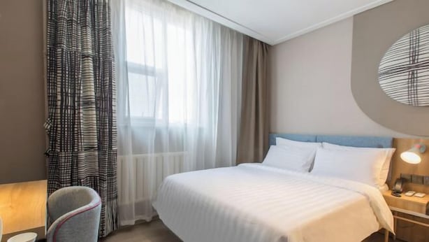 A hotel room with a bed, a chair, a nightstand with a lamp, and a window with curtains. - Homeinn Hotel (Weifang Xinhua Road Shengli East Street City Government Plaza) (Weifang)
