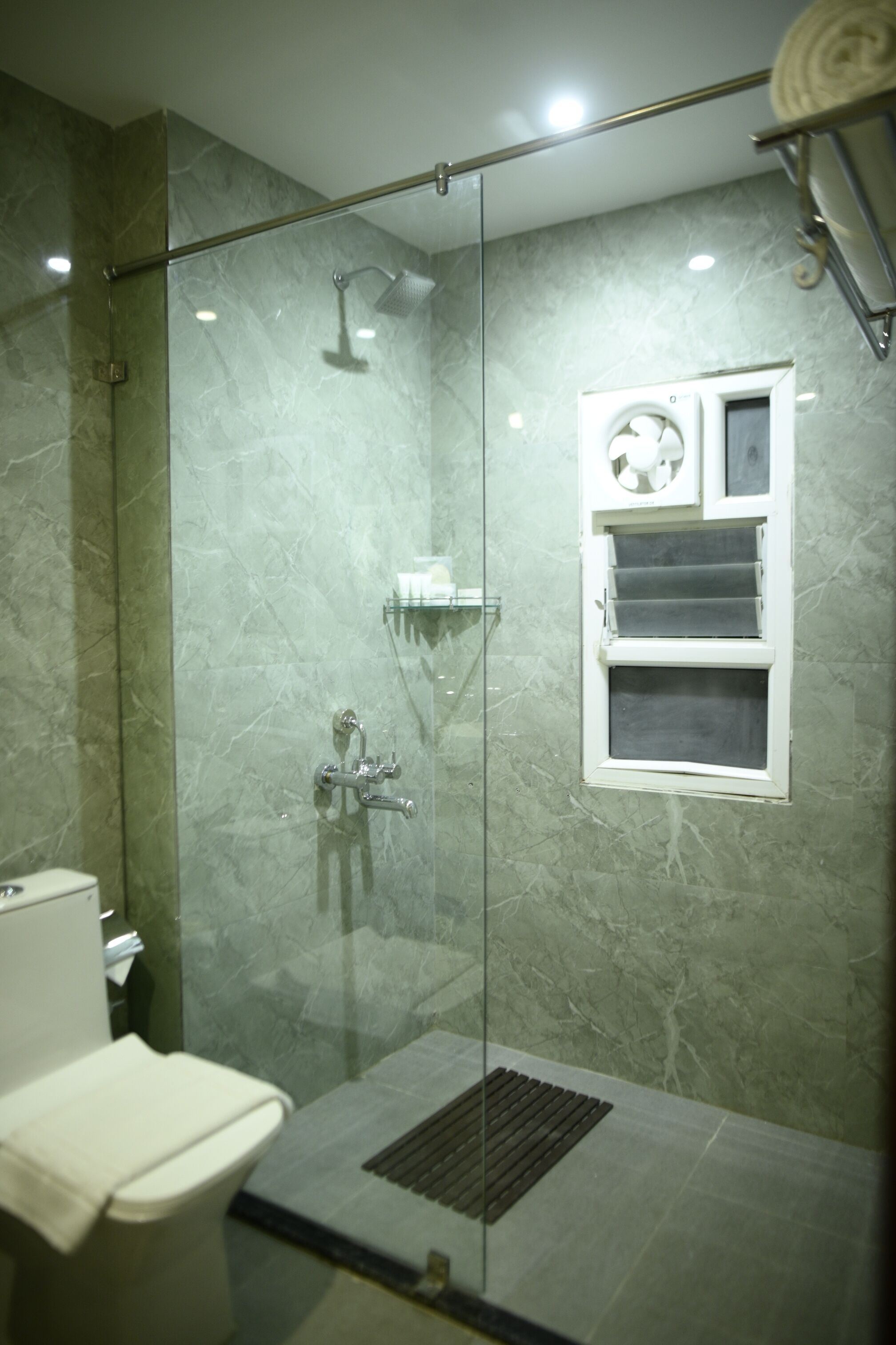 A modern bathroom with a glass-enclosed shower, a toilet, and a built-in sink.