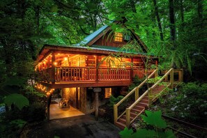 Een houten chalet met balkon, omringd door dicht bos.