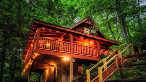 Un chalet rustique doté d’un balcon en bois, d’un escalier et d’une entrée en pierre.