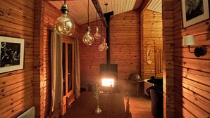 Ein Holzinterieur mit einem langen Esstisch, hängenden Lampen und einem sichtbaren Kamin.