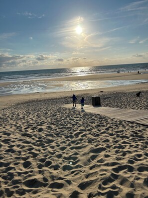 Een zandstrand met voetafdrukken en een houten looppad.
