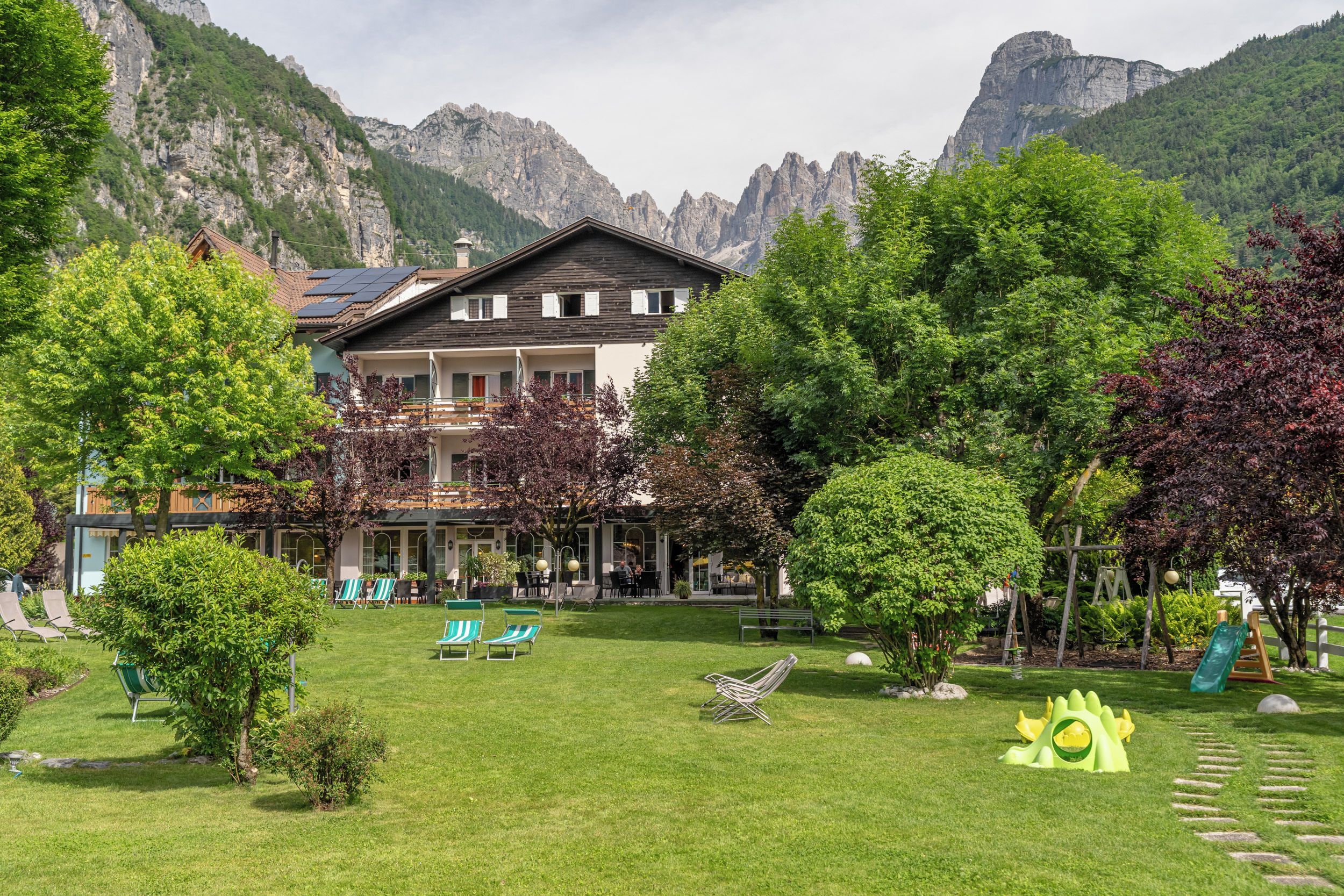 Ein Hotel mit Garten, Sitzgelegenheiten im Freien und Blick auf die Berge.