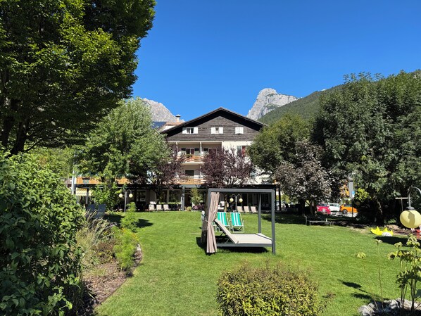 Un hôtel doté d’une pelouse bien entretenue, d’un espace extérieur aménagé pour s’asseoir et offrant une vue sur les montagnes.