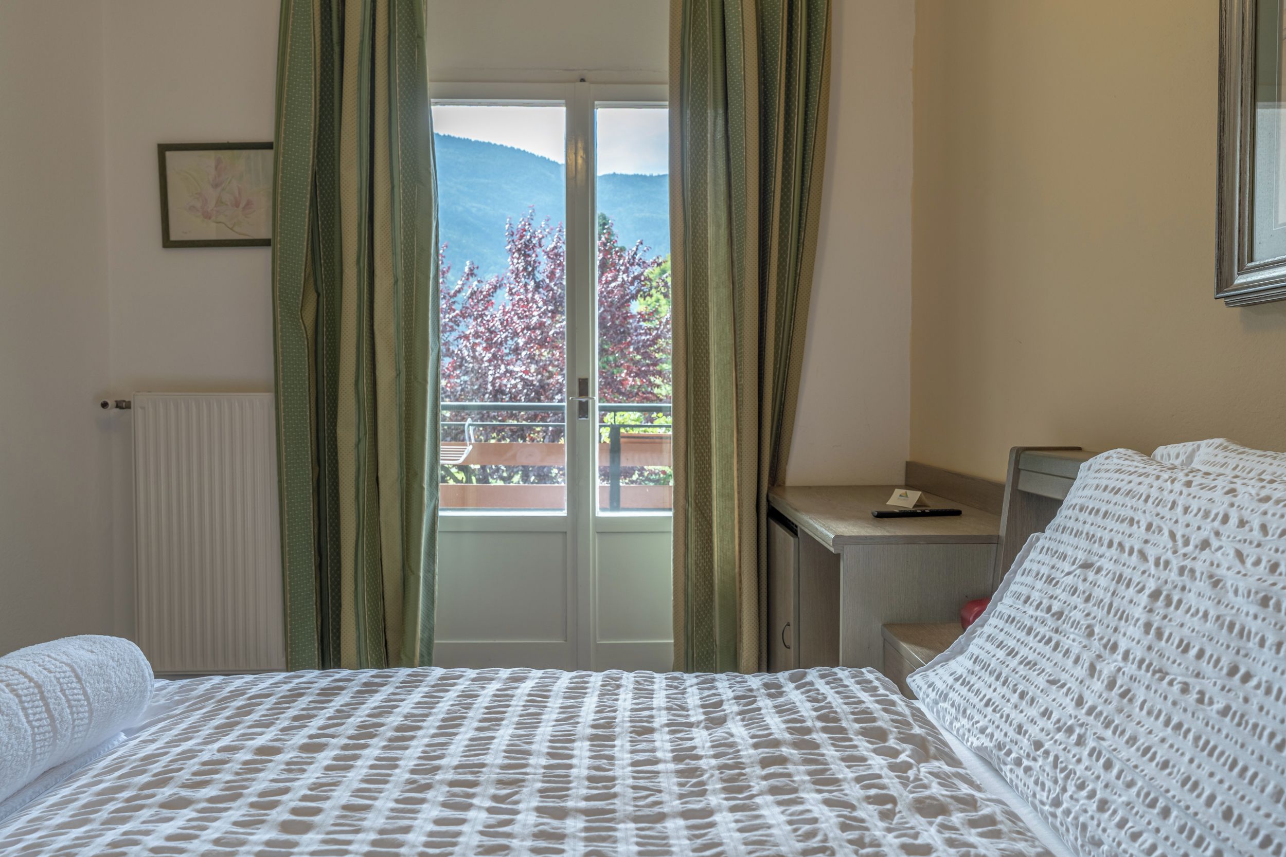 A hotel room with a bed, a desk, and a view of mountains through the window.