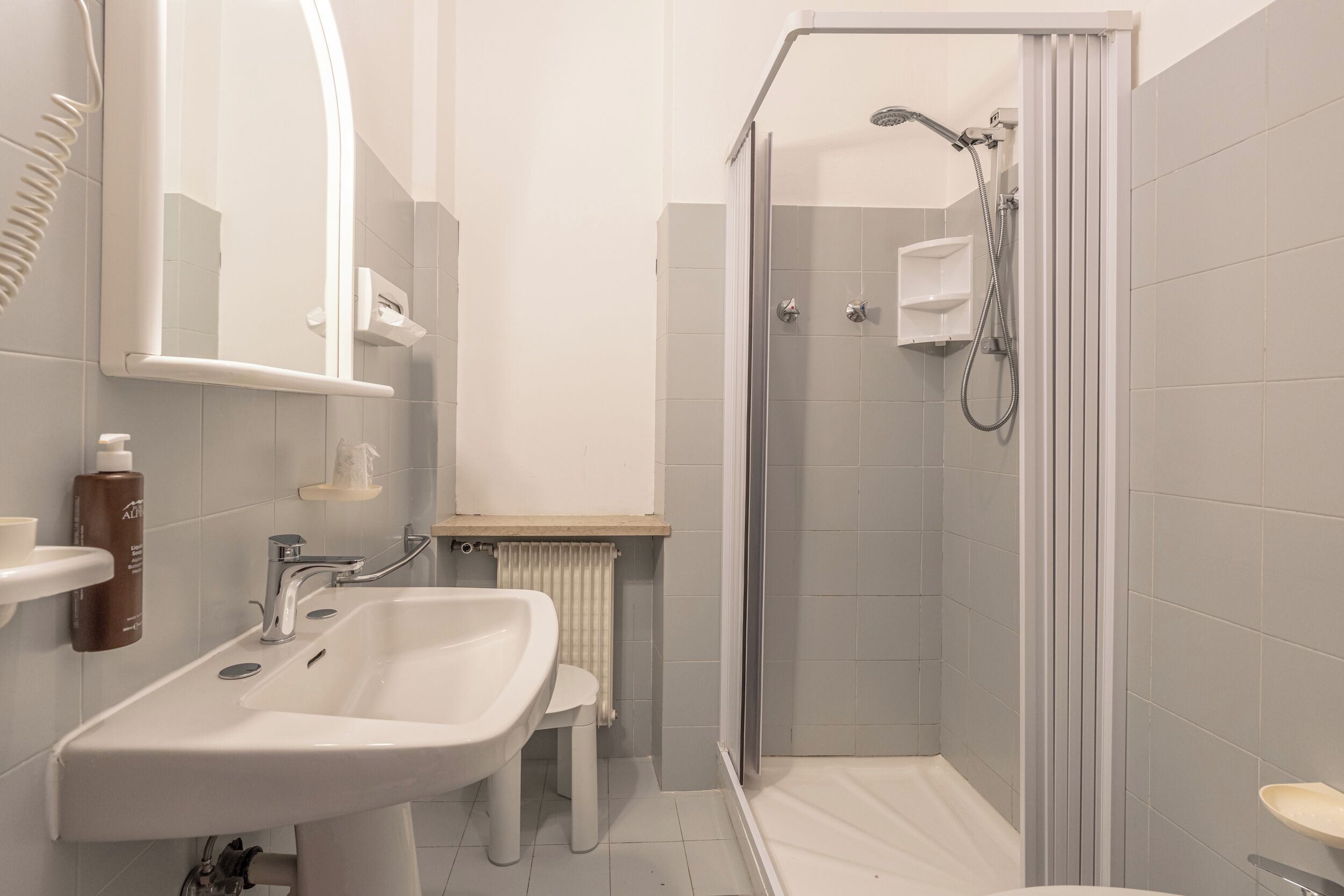 Un baño moderno con ducha, lavamanos y espejo.