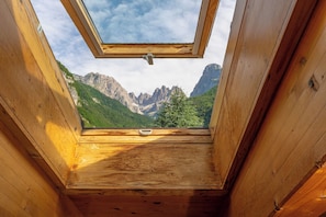 A wooden room with a skylight, a wooden bench, and a view of mountains. - Garden Hotel Bellariva (Molveno)