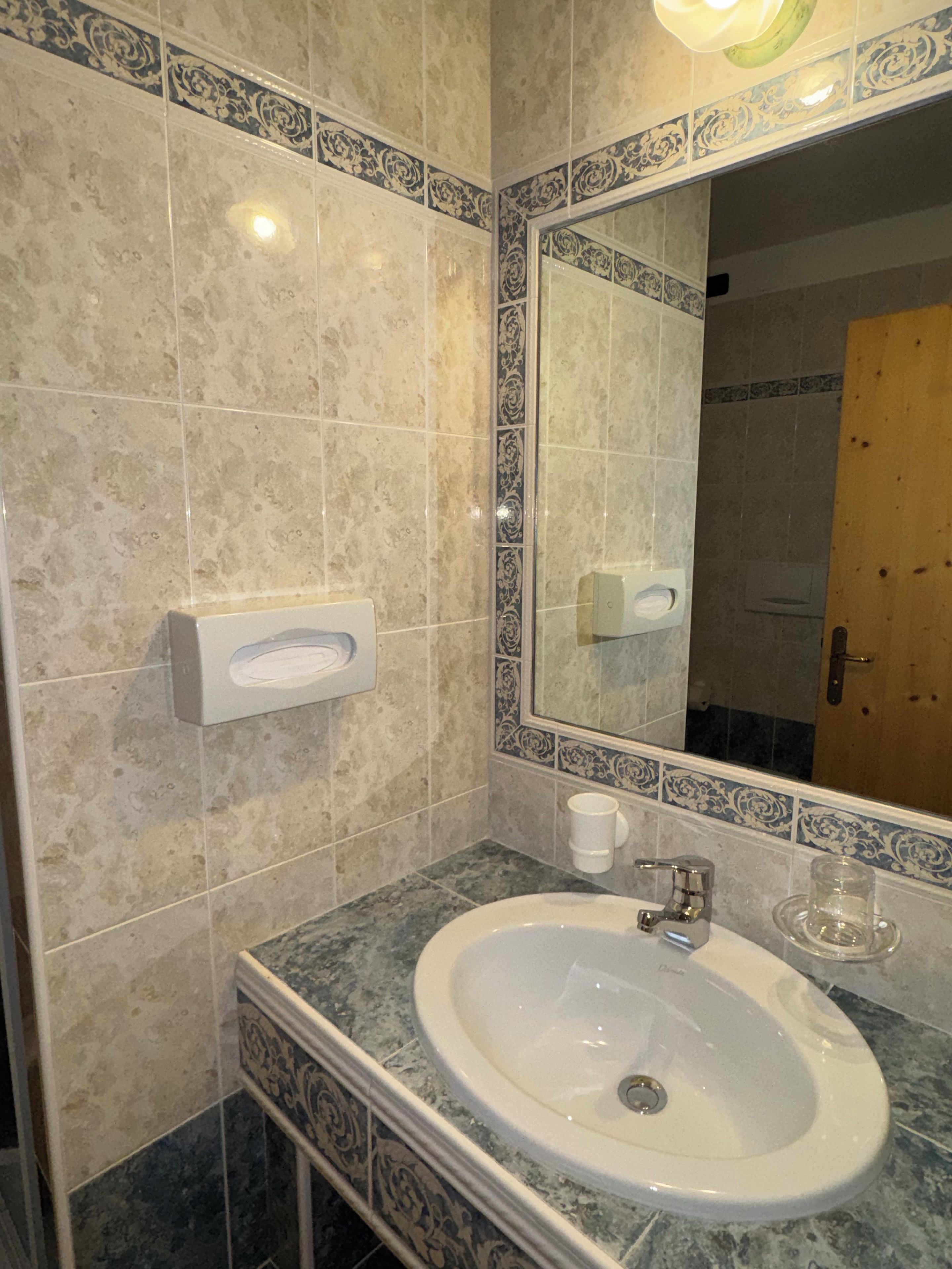 Un baño con lavamanos, espejo y azulejos decorativos.