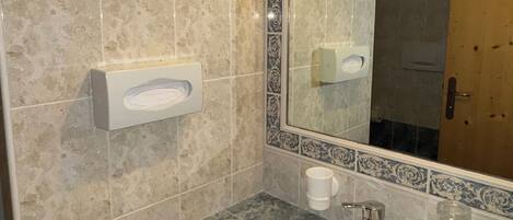 A bathroom with a sink, mirror, and decorative tiles.