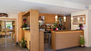 Een houten receptiebalie met een bar, een klok en een kunstwerk in een lijst aan de muur.