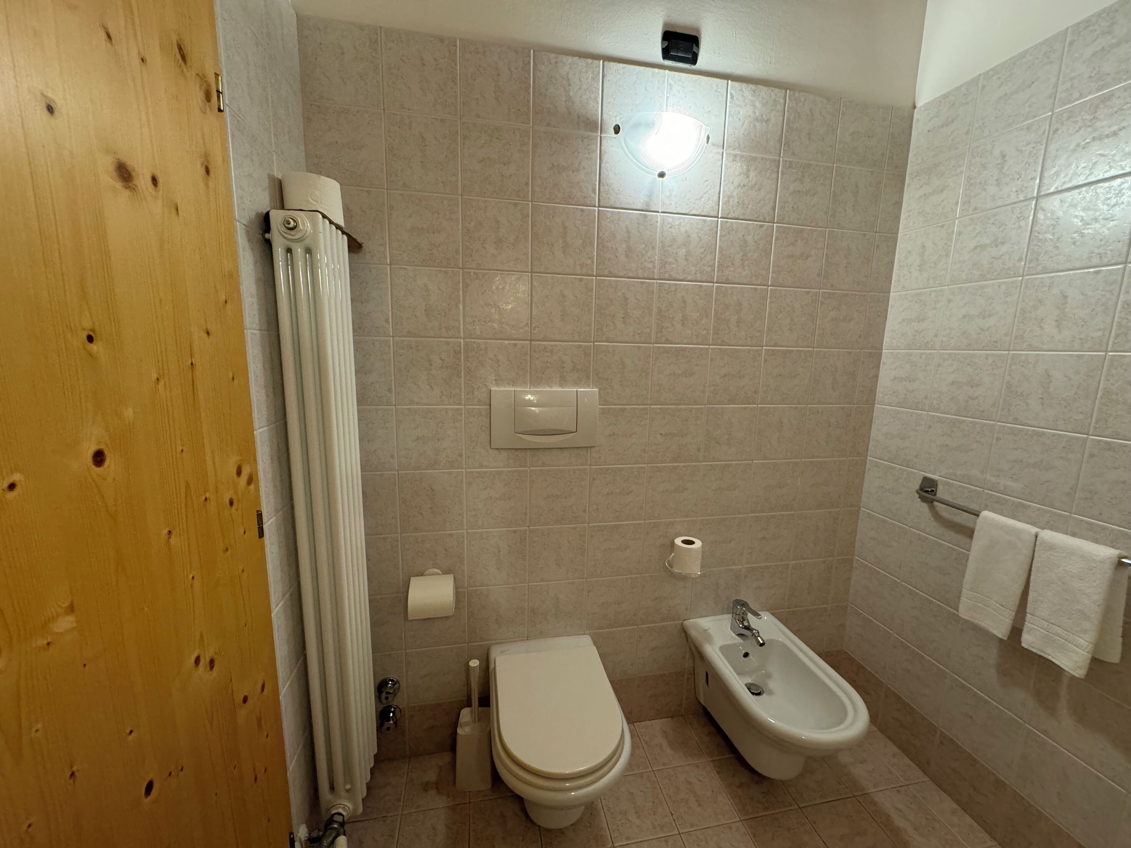A bathroom with a toilet, bidet, and towel rack.