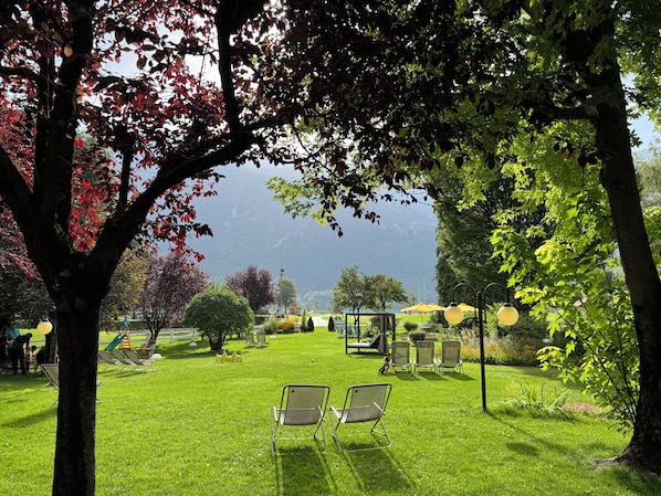 Un parque con césped, árboles y mesas al aire libre.
