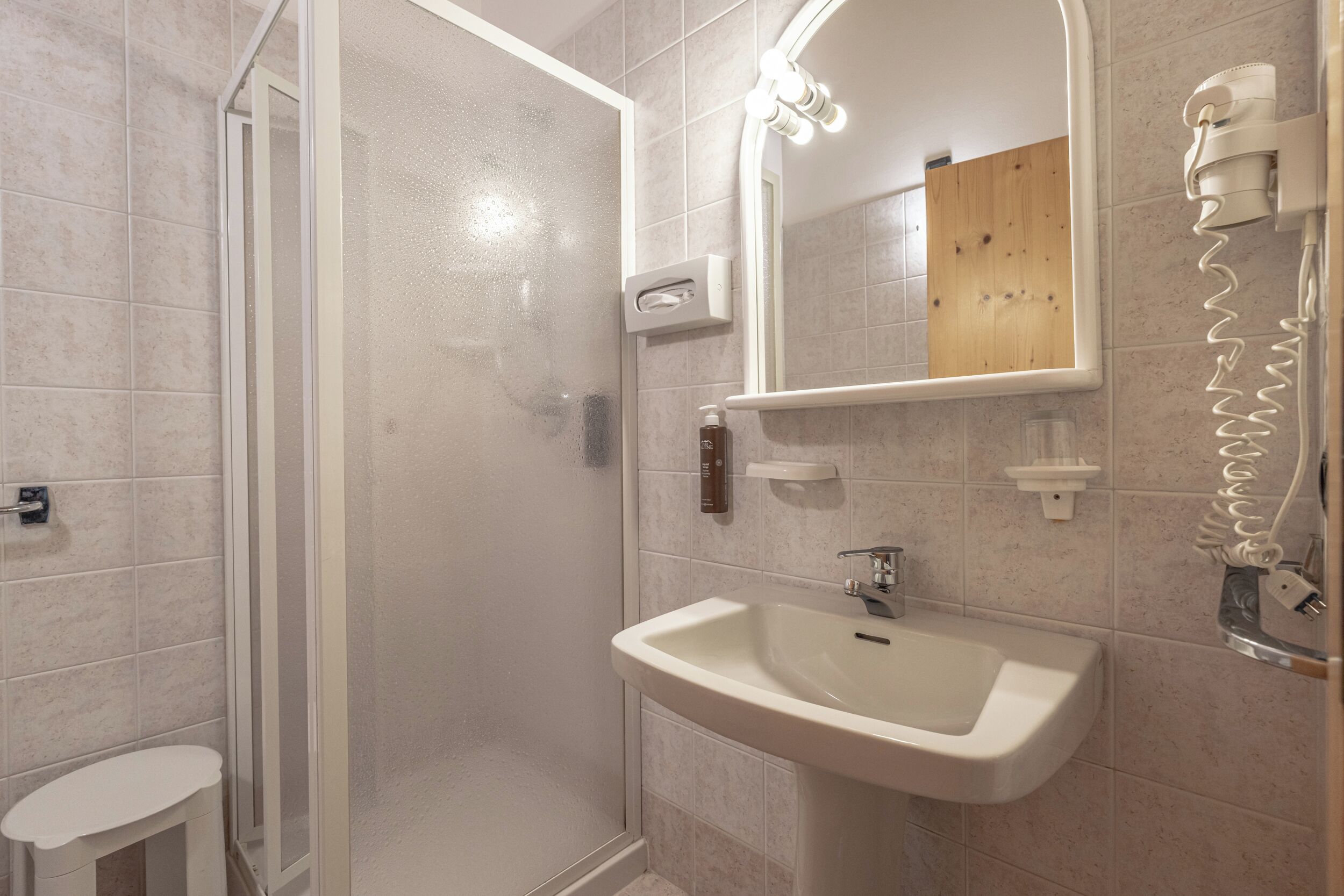 A bathroom with a shower, sink, and mirror.