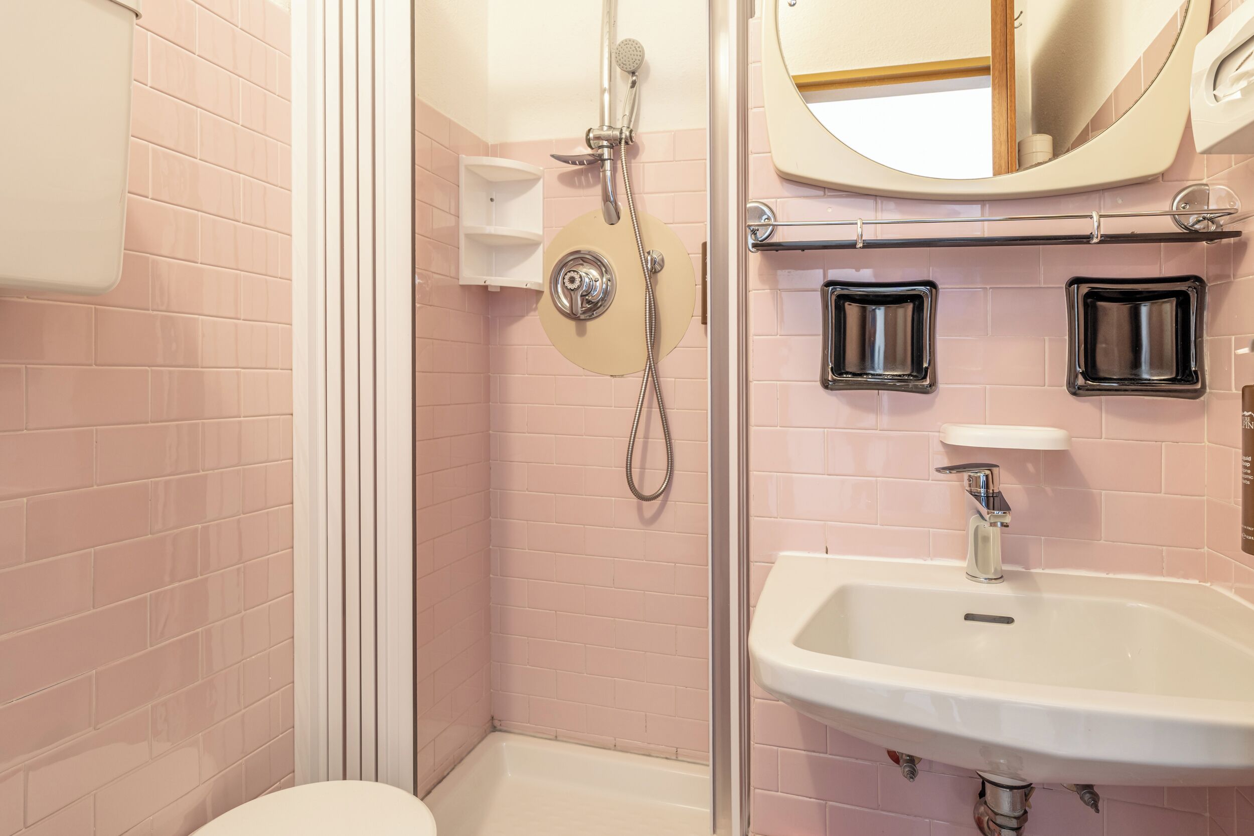 A bathroom with a shower, toilet, sink, and mirror.
