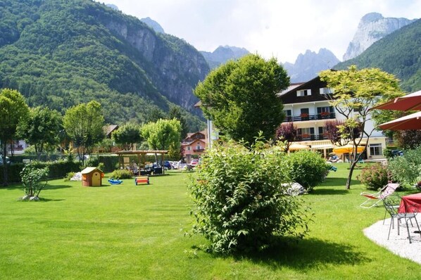 Un hotel con vistas a la montaña, con terraza al aire libre y una pequeña zona de juegos.
