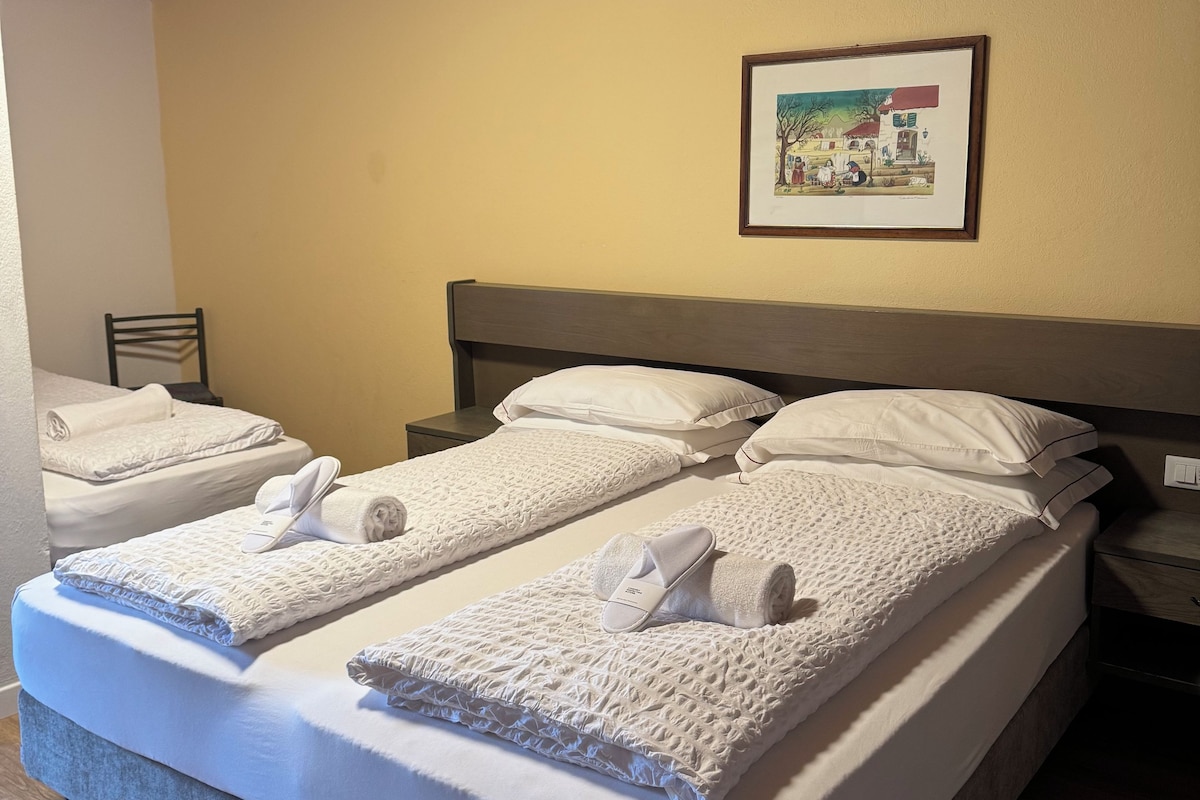 A hotel room with a double bed, a headboard, a framed picture on the wall, and a wooden ceiling.
