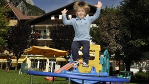 A child playing on a playground with a mountain backdrop.