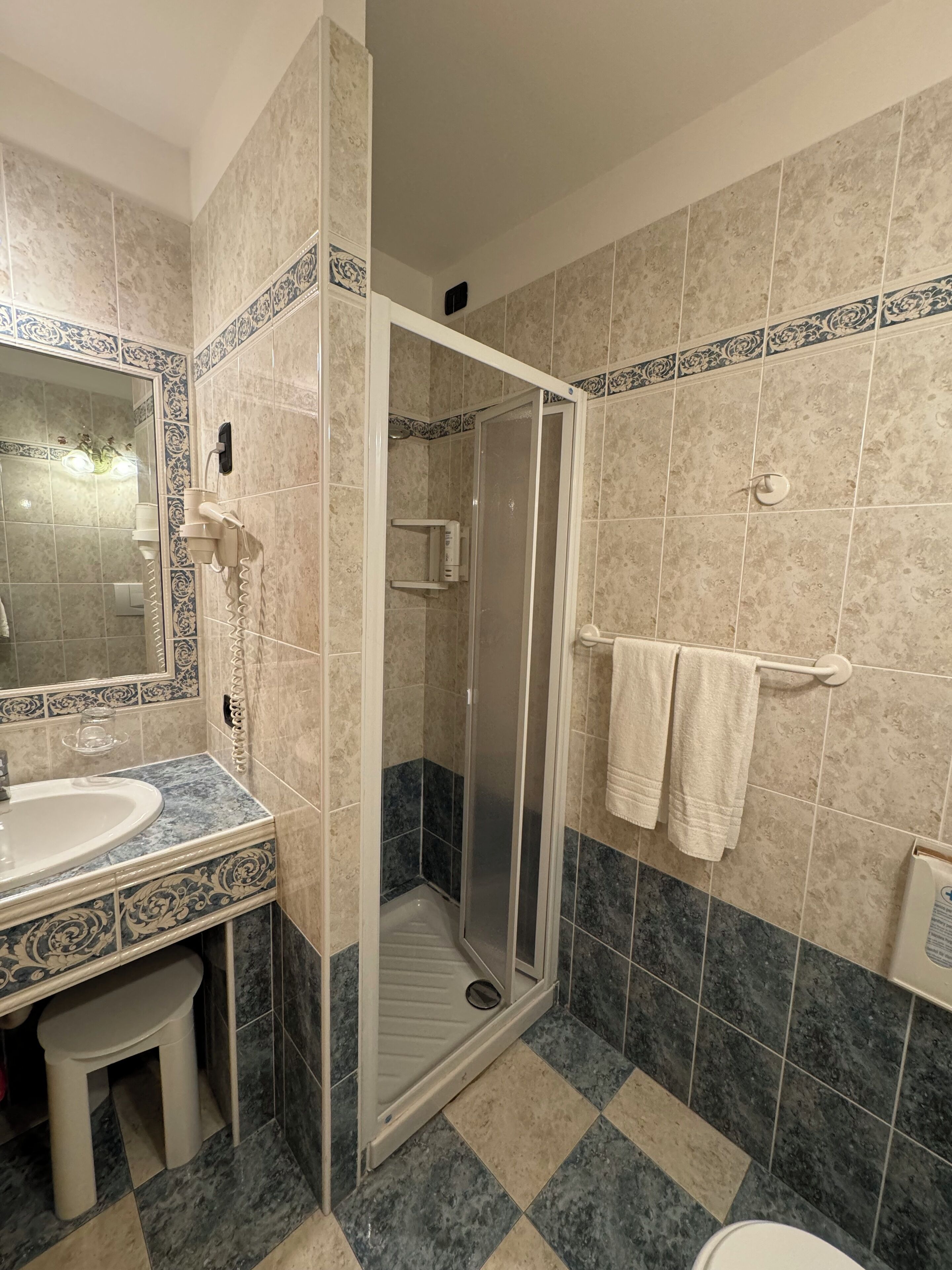 Un baño con ducha, lavabo y toallero.