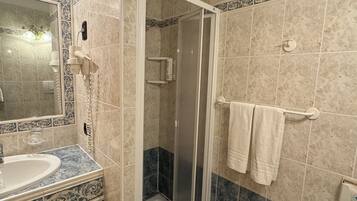 Un baño con ducha, lavabo y toallero.