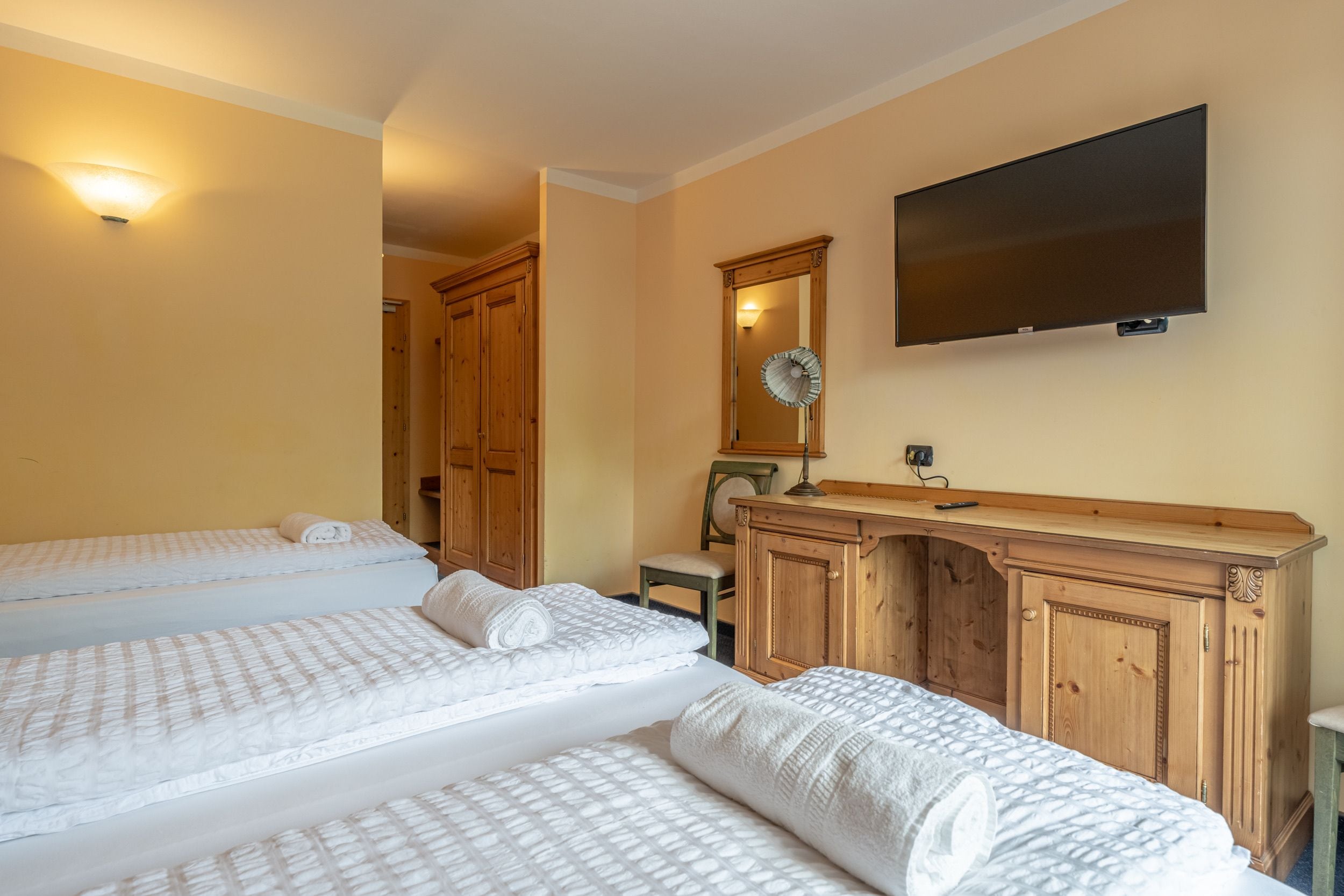 A hotel room with two beds, a wooden dresser, a flat-screen TV, and a mirror.