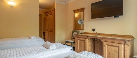 A hotel room with two beds, a wooden dresser, a flat-screen TV, and a mirror.