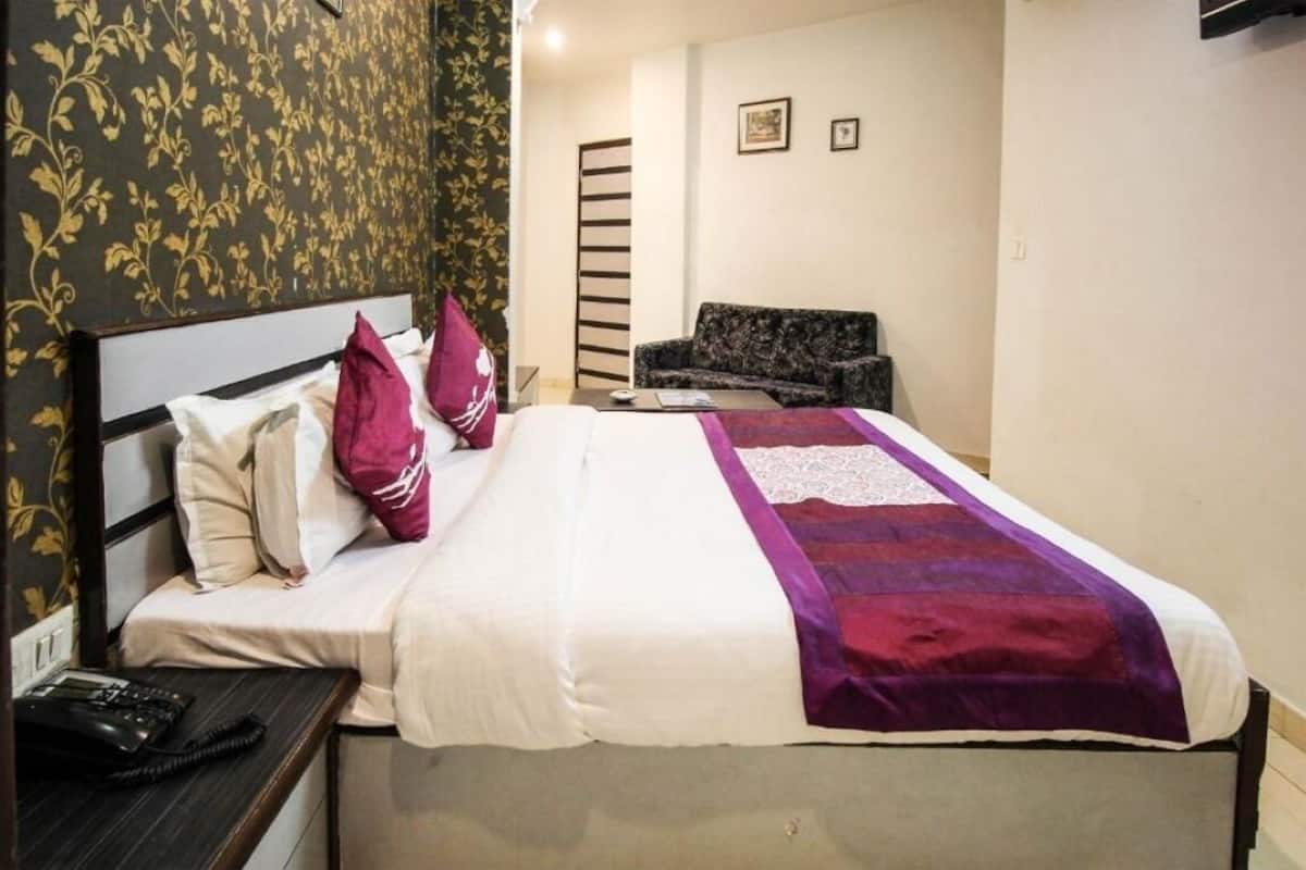 A hotel room with a bed, a desk, a chair, and a sofa.