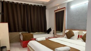 A hotel room with two beds, a red and white color scheme, a large mirror, and a view of the cityscape. - Hotel Liberty (Ahmedabad)