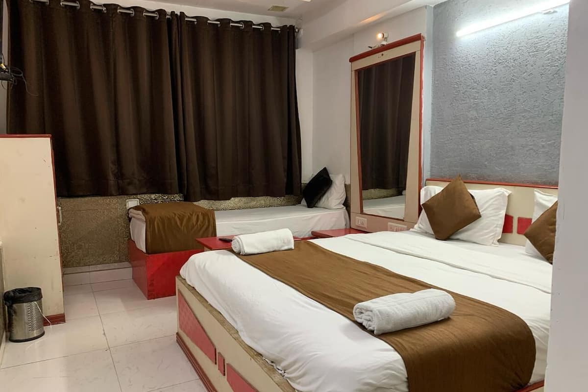 A hotel room with two beds, a red and white color scheme, a large mirror, and a view of the cityscape.