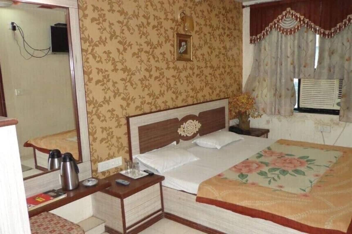A bedroom with a bed, bedside table, and a mirror.