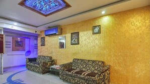 A lobby with patterned sofas, a decorative ceiling, and framed artwork on the walls. - Hotel Liberty (Ahmedabad)