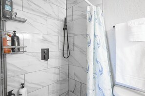 Ein Badezimmer mit Dusche, Handtuchhalter und Pflegeprodukten auf einem Regal.